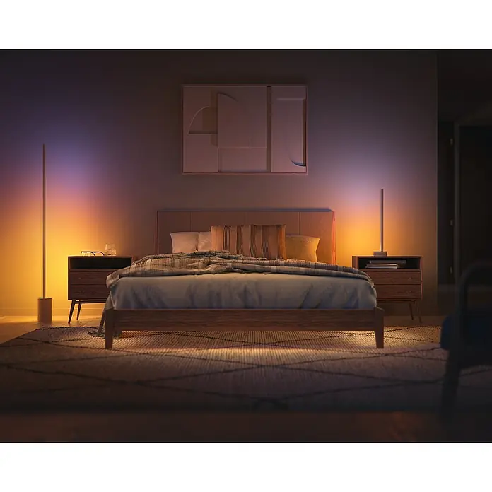 Philips Hue LED-Tischleuchte Signe Oak - 12 W, L x B x H: 11,15 x 11,15 x 55,3 cm, Weiß, RGBW - Ein stilvolles Schlafzimmer mit einem modernen Bett, Nachttischen und stimmungsvoller Beleuchtung. Die schlanke Stehlampe sorgt für warmes Licht.