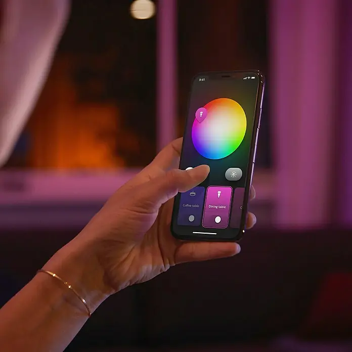 Philips Hue LED-Einbauspot White & Color Ambience Slim Recessed S - 8,3 W, RGBW, Durchmesser: 9 cm, 1 Stk., Schwarz - Ein Smartphone mit einer App zur Steuerung von intelligenten Glühbirnen, das eine Farbpalette zeigt, um die Beleuchtung anzupassen.