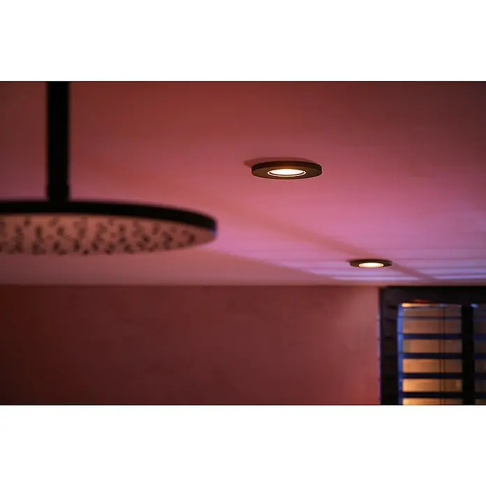 Philips Hue LED-Einbauspot White & Color Ambiance Xamento - RGBW, Durchmesser: 9,4 cm, Schwarz - Deckenleuchten und Duschkopf in einem modernen Badezimmer. Die Leuchten sorgen für eine angenehme Beleuchtung.