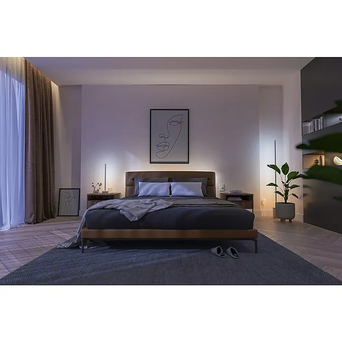 Philips Hue LED-Tischleuchte Signe Oak - 12 W, L x B x H: 11,15 x 11,15 x 55,3 cm, Weiß, RGBW - Ein Schlafzimmer mit einem modernen Bett mit Beleuchtung und einem stilvollen Nachtisch, betont durch minimalistische Kunst.