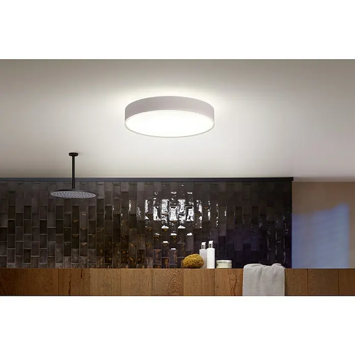 Philips Hue LED-Deckenleuchte rund Devere - 34 W, Ø x H: 47,6 x 10 cm, Weiß, Neutralweiß - Deckenleuchte in einem Badezimmer. Runde Deckenleuchte sorgt für Helligkeit, während eine dunkle Fliesenwand und eine Regendusche Eleganz bieten.