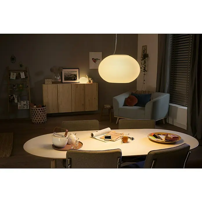 Philips Hue LED-Pendelleuchte Flourish - 39,5 W, L x B x H: 40,1 x 40,1 x 30 cm, Weiß - Ein sanft beleuchtetes Esszimmer mit einem runden Esstisch und einer eleganten Pendelleuchte, die ein gemütliches Ambiente schafft.