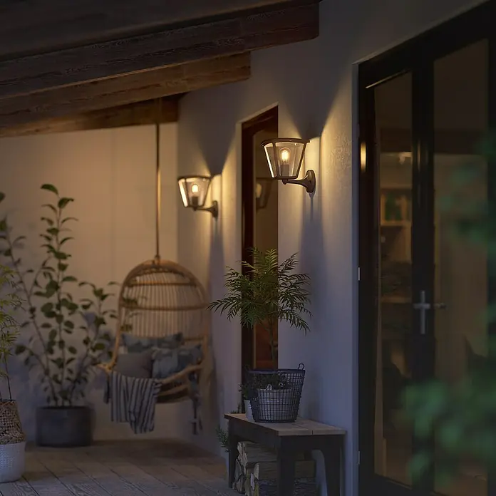 Philips Hue LED-Wandleuchte Inara - 7 W, L x B x H: 21,9 x 22,6 x 27,7 cm, Schwarz, Warmweiß - Ein stilvolles Außenbereich-Arrangement mit zwei Wandleuchten, die ein warmes Licht ausstrahlen und eine einladende Atmosphäre schaffen.