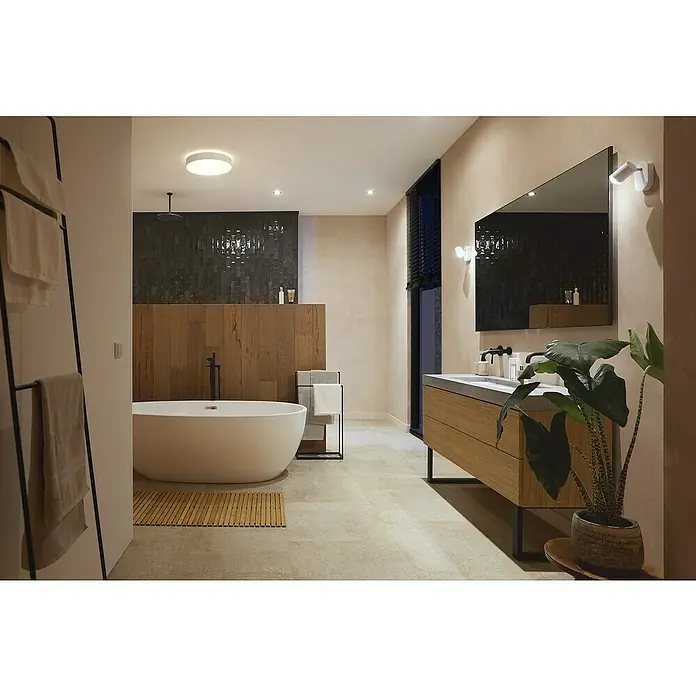 Philips Hue LED-Deckenleuchte rund Devere - 34 W, Ø x H: 47,6 x 10 cm, Weiß, Neutralweiß - Ein modernes Badezimmer mit einer freistehenden Badewanne, einem Waschtisch mit Spiegel und Zimmerpflanze, beleuchtet von Decken- und Wandleuchten.