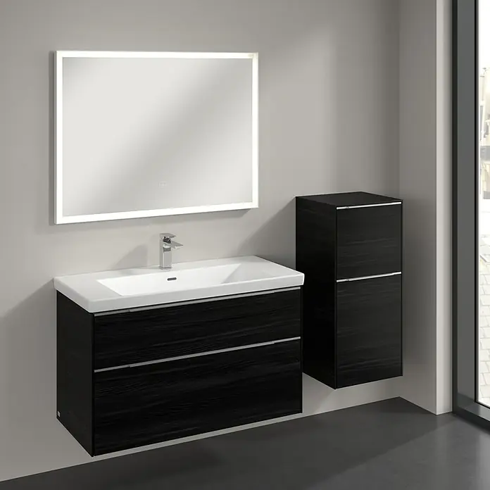 Villeroy & Boch Subway 3.0 Seitenschrank - B x T x H: 40 x 36,2 x 86 cm, Black Oak, DIN Anschlag: Rechts, Farbe Griff: Aluminium glänzend - Das Bild zeigt ein Badezimmer-Waschbecken mit Unterschrank und einem beleuchteten Spiegel, sowie einem passenden Hängeschrank in dunklem Holzdekor.