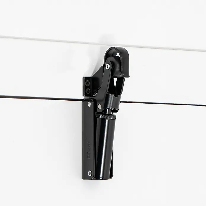 Justor Retenedor para puerta y ventana FR1 - Negro, Carga soportada: 6 kg - Primer plano de un amortiguador de puerta de armario negro montado en un armario blanco, diseñado para un cierre suave.