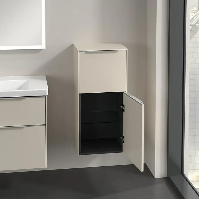 Villeroy & Boch Subway 3.0 Seitenschrank - B x T x H: 40 x 36,2 x 86 cm, Cashmere Grey, DIN Anschlag: Rechts, Farbe Griff: Aluminium glänzend - Das Foto zeigt ein Badezimmer mit einem beigefarbenen Waschbeckenunterschrank und einem offenen, beigefarbenen Hängeschrank mit schwarzen Innenregalen.