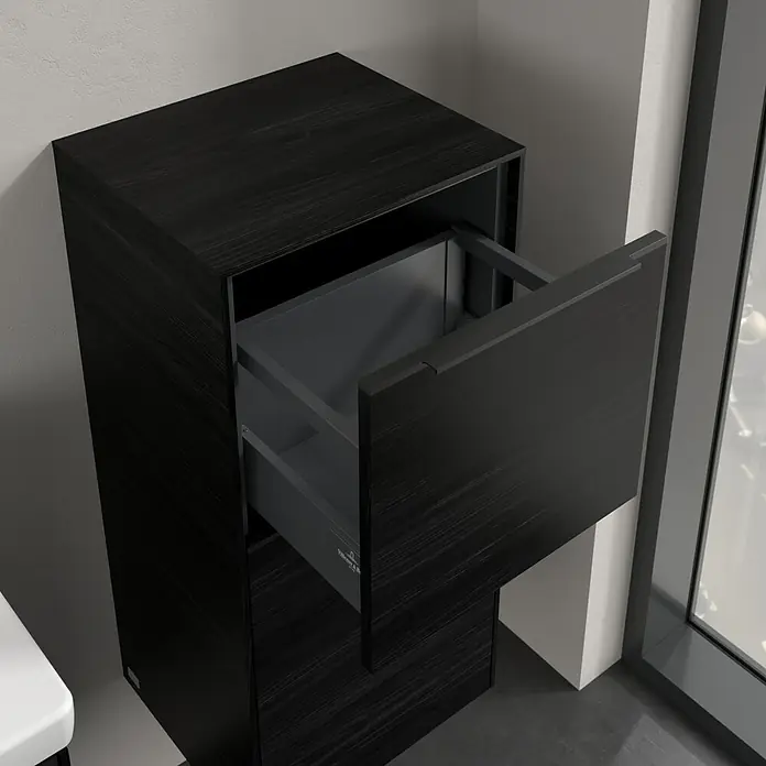 Villeroy & Boch Subway 3.0 Seitenschrank - B x T x H: 40 x 36,2 x 86 cm, Black Oak, DIN Anschlag: Rechts, Farbe Griff: Volcano Black - Aufnahme eines modernen, dunklen Holzschranks mit einer teilweise geöffneten Schublade, der modernes Design und Funktionalität vereint.