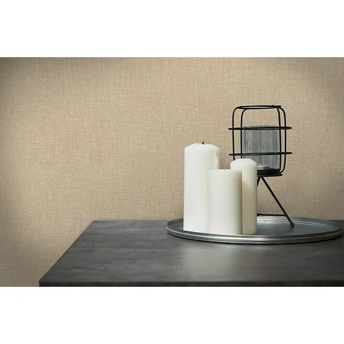 A.S. Création Metropolitan Stories Vliestapete Textil-Optik - Braun/Beige, Uni, 10,05 x 0,53 m - Elegante Stillleben-Szene mit weißen Kerzen, einem Windlicht und einem silbernen Tablett auf einem Tisch vor einem texturierten Hintergrund.