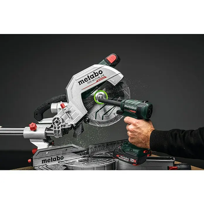 Metabo CAS 18V Akku-Blaspistole BP 18 LTX BL - Ohne Akku, Luftmenge: 0,7 m³/min - Die Metabo KGS 18 LTX BL 216 Akku-Kapp- und Gehrungssäge in Aktion, mit Staubpartikeln beim Sägen, präsentiert Leistung und Präzision.