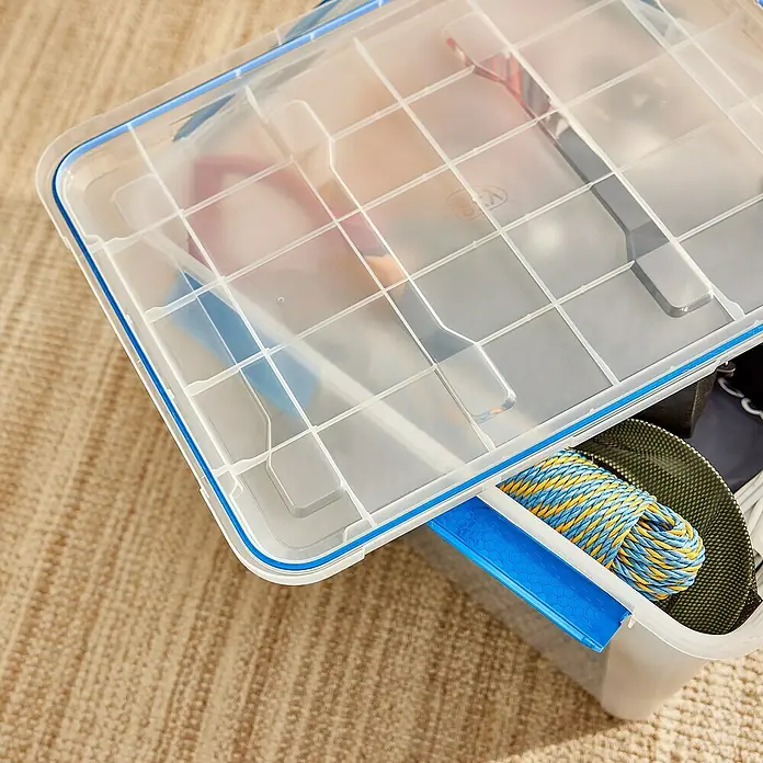 Aufbewahrungsbox Wasserdicht - L x B x H: 66,6 x 46,9 x 45,9 cm, Kunststoff, Transparent - Eine blaue und transparente Aufbewahrungsbox mit diversen Gegenständen darin, die auf einem Teppich steht.
