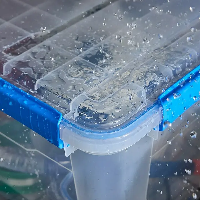 Aufbewahrungsbox Wasserdicht - L x B x H: 57,8 x 38,2 x 21,7 cm, Kunststoff, Transparent - Nahaufnahme einer wasserdichten Aufbewahrungsbox mit blauem Verschluss, die mit Wassertropfen bedeckt ist und ihre Dichtigkeit demonstriert.