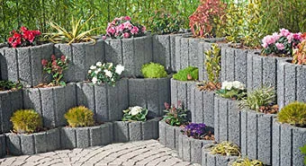 Mauer aus anthrazit Pflanzringen mit Blumen bepflanzt