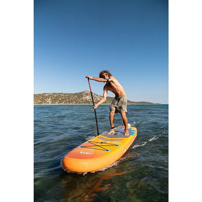 Aqua Marina SUP-Board Turbo - L x B x H: 366 x 84 x 15 cm, Nutzlast: 170 kg, 1 Stk., Aufblasen - Ein Mann paddelt auf einem orangefarbenen Aqua Marina Turbo SUP auf dem Wasser, umgeben von einer malerischen Küstenlandschaft.