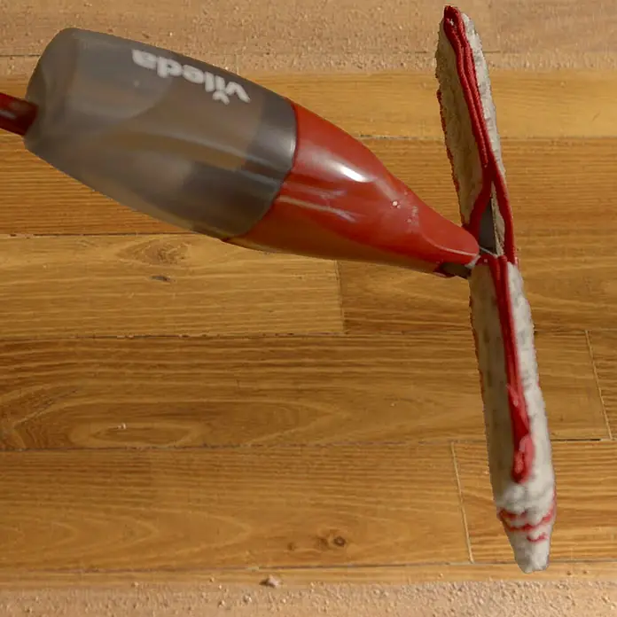 Vileda Bodenwischer Spray & Clean Sprühwischer - 2 -tlg. - Nahaufnahme eines Vileda-Sprühmopps, der zum Reinigen von Holzböden verwendet wird, mit Fokus auf den Moppkopf und den Sprühmechanismus.