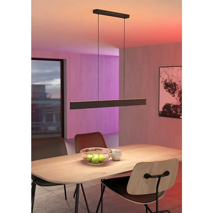 Eglo LED-Pendelleuchte Andreas-Z - 38 W, L x B x H: 117 x 7 x 110 cm, Schwarz, RGBW - Eine moderne, schwarze Pendelleuchte hängt über einem Holztisch mit Obstschale, der von stilvollen Stühlen umgeben ist.