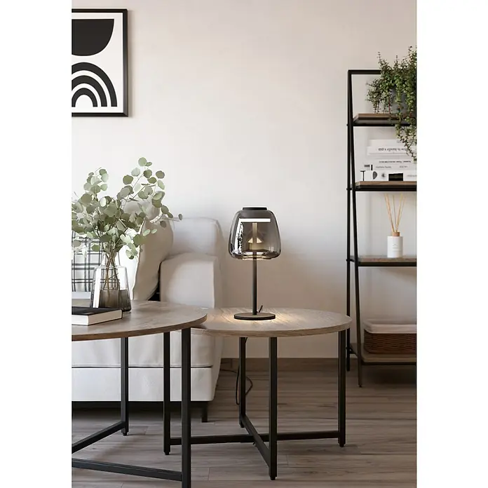 Eglo connect.z LED-Tischleuchte Alfero-Z - 7,7 W, L x B x H: 16,5 x 16,5 x 34,5 cm, Schwarz, RGBW - Nahaufnahme einer eleganten rauchfarbenen Tischlampe auf einem runden Beistelltisch, die eine moderne Wohnraumdekoration hervorhebt.