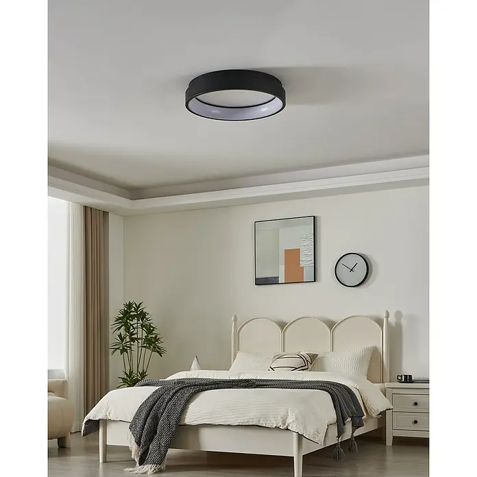 Eglo connect.z LED-Deckenleuchte rund Marghera-Z - 26 W, Ø x H: 60 x 11 cm, Schwarz, RGBW - Eine moderne, runde Deckenleuchte in Schwarz und Weiß hängt in einem Schlafzimmer mit einem Bett und einem Gemälde an der Wand.