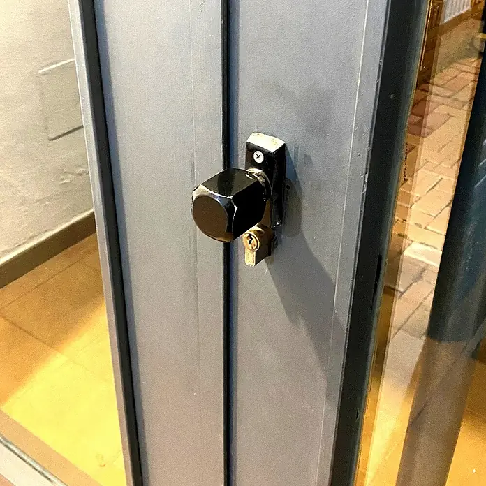 Micel Brimic Pomo giratorio 6807 - Aluminio, Negro - Primer plano de una cerradura de puerta con un pomo negro y una llave insertada en el mecanismo de cierre.