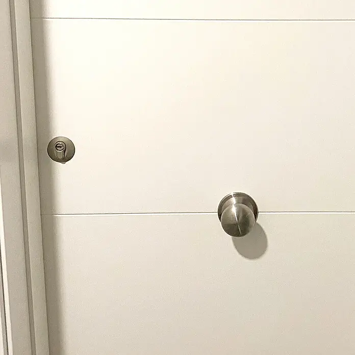 Micel Pomo giratorio 11904 - Latón - Primer plano de una puerta blanca moderna con un pomo plateado y un ojo de cerradura, destacando su diseño elegante y funcionalidad.