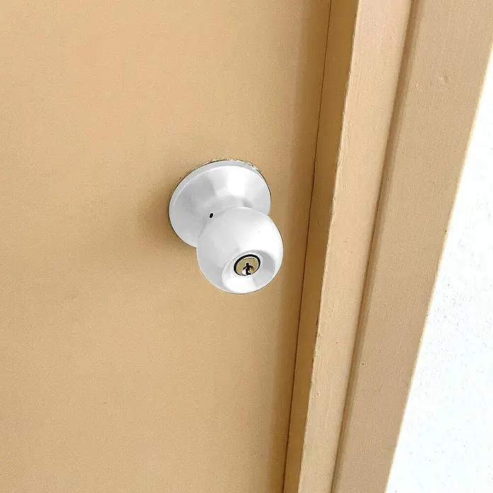 Micel Brimic Pomo giratorio de entrada PP7 - Acero inoxidable, Blanco - Primer plano de un pomo de puerta redondo y blanco en una puerta, mostrando su diseño simple y funcional.