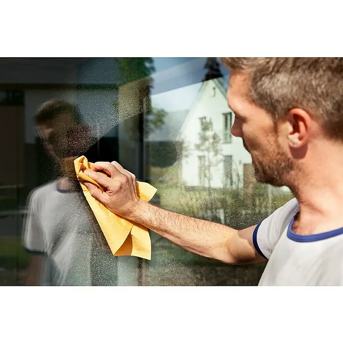 Vileda Original Fenstertuch - 40 x 36 cm, Mikrofaser - Ein Mann putzt mit einem gelben Tuch eine Fensterscheibe, die das Licht reflektiert und die Sauberkeit hervorhebt.