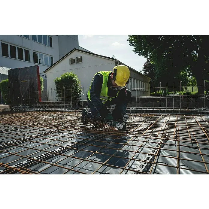 Metabo CAS 18V Akku-Winkelschleifer W 18 7-125 - Ohne Akku, Durchmesser Scheibe: 125 mm - Bauarbeiter mit Schutzhelm und Arbeitskleidung beim Schneiden von Metall mit einem Metabo Winkelschleifer auf einer Baustelle.