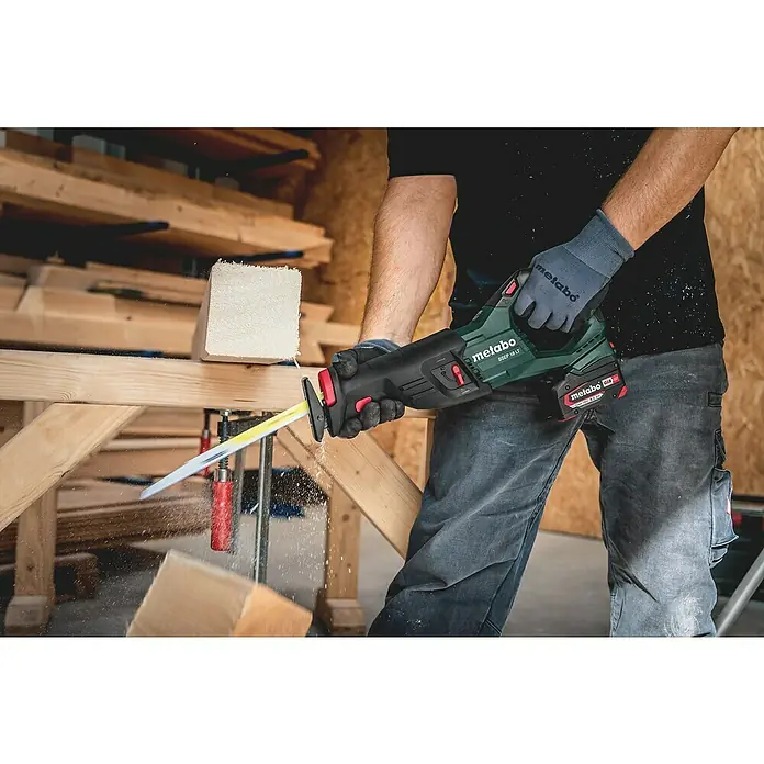 Metabo CAS 18V Akku-Säbelsäge SSEP 18 LT - 18 V, Ohne Akku - Ein Arbeiter sägt ein Holzstück mit einer Metabo SSEP 18 LT Akku-Säbelsäge, wobei Holzspäne fliegen und die Säge im Fokus steht.