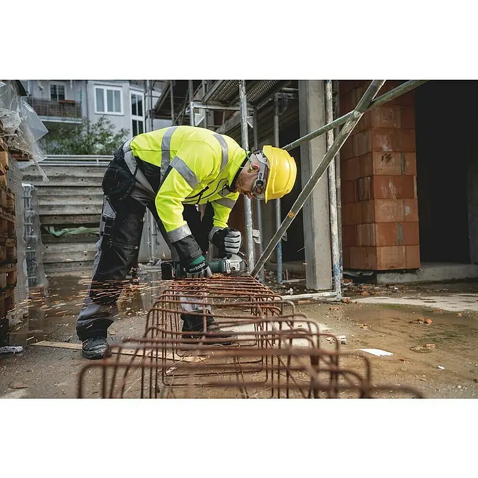 Metabo CAS 18V Akku-Winkelschleifer W 18 7-125 - Ohne Akku, Durchmesser Scheibe: 125 mm - Ein Bauarbeiter in Sicherheitsausrüstung benutzt einen Metabo Winkelschleifer, um Metall zu schneiden, wobei Funken fliegen.
