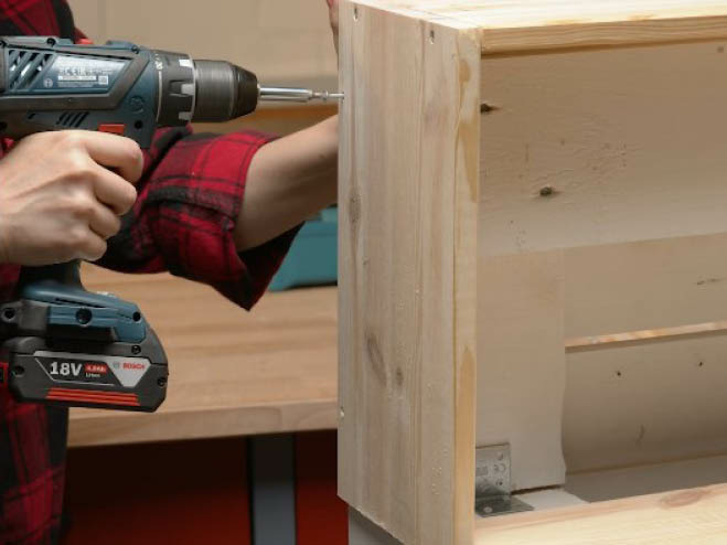 Die Holzverkleidung wird an die Palette geschraubt