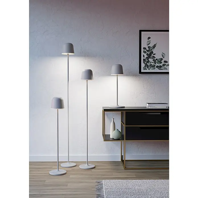 Eglo LED-Stehleuchte Mannera-L - 4,3 W, Höhe: 140 cm, Grau, Tageslichtweiß - Eine Gruppe grauer LED-Stehlampen und eine Tischlampe vor einer Wand und einem schwarzen Sideboard.
