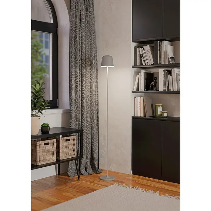 Eglo LED-Stehleuchte Mannera-L - 4,3 W, Höhe: 140 cm, Grau, Tageslichtweiß - Eine moderne Stehlampe in Grau steht neben einem Fenster und einem Bücherregal. Die Lampe sorgt für gemütliches Licht im Raum.