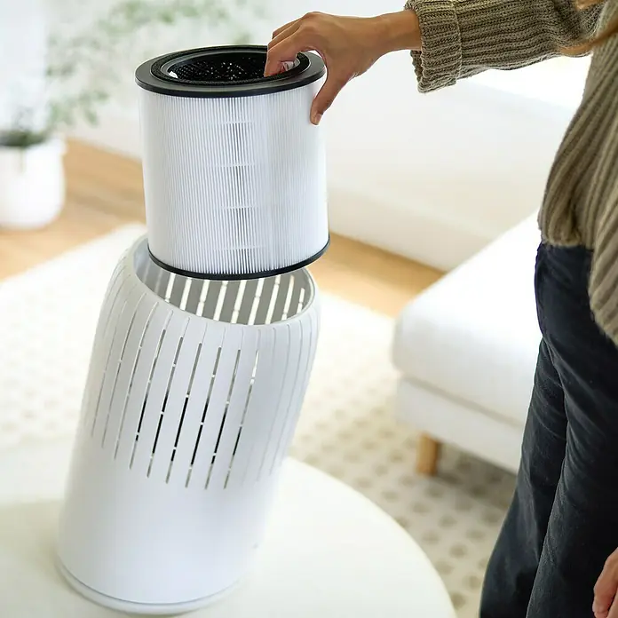 Bosch Ersatzfilter Air 4000 - Passend für: Luftreiniger Air 4000 und Air 4000i - Eine Person setzt einen Filter in einen Luftreiniger ein. Der Luftreiniger ist weiß und steht auf einem Tisch.