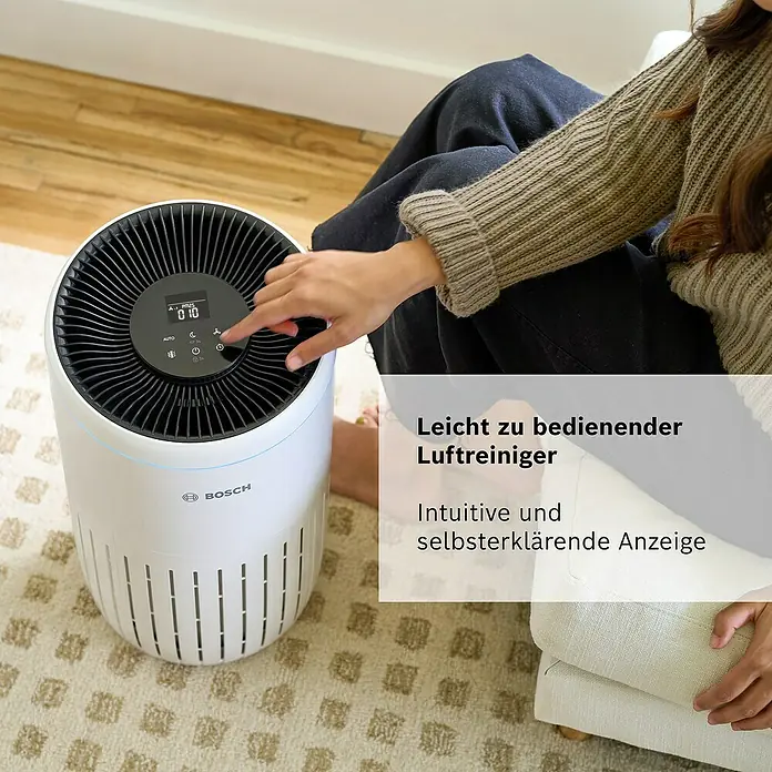 Bosch Luftreiniger Air 4000 - Raumgröße: 62,5 m², 29,1 x 50 cm - Eine Frau bedient einen Bosch Luftreiniger, dessen intuitives Display und einfache Bedienung hervorgehoben werden.