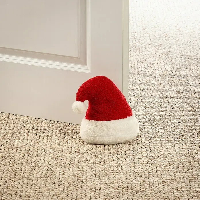 Türstopper Santa Xmas - 18 x 12 x 21 cm, Rot/Weiß - Weihnachtliche Türstopper: Ein roter und weißer Weihnachtsmannhut hält eine Tür auf einem beigen Teppich offen.