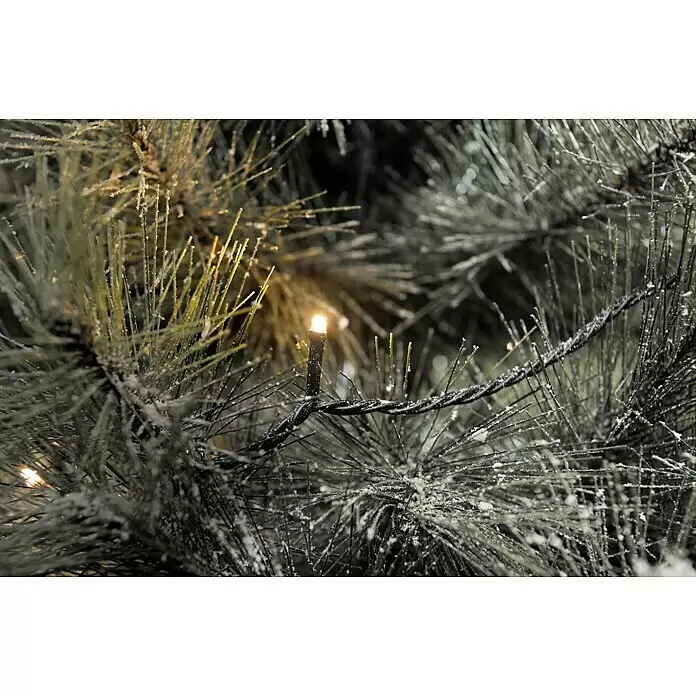 Konstsmide LED-Lichterkette Micro LED - Außen, Lichtfarbe: Bernstein, Anzahl Leuchtmittel: 80 Stk., Netzbetrieben - Nahaufnahme von künstlichen Kiefernzweigen, mit weißem Schnee bedeckt, verziert mit einer schwarzen Lichterkette aus warmweißen LEDs.