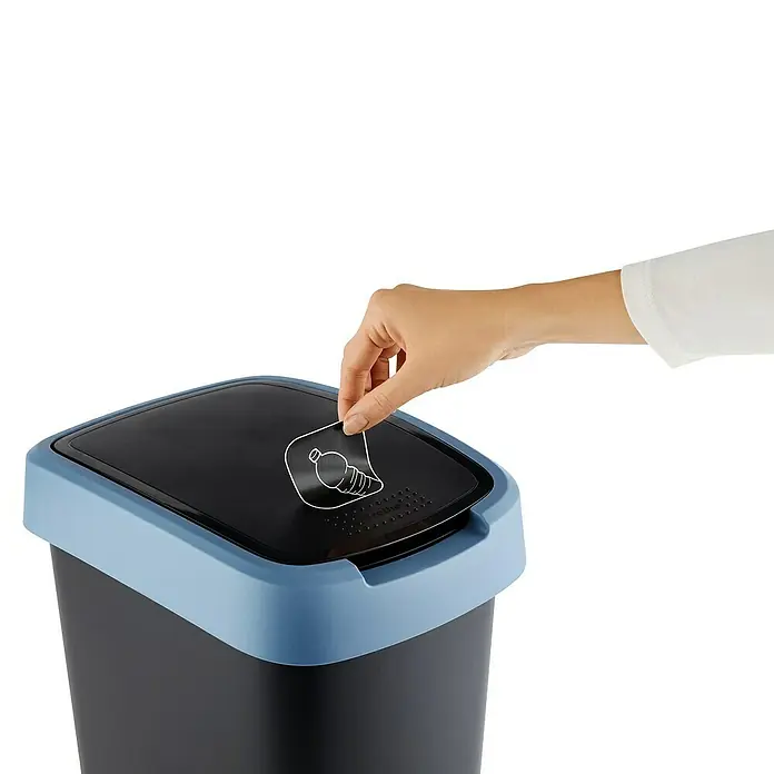 Rotho Schwingdeckeleimer Twist - 10 l, Kunststoff, Horizont Blau - Eine Hand entfernt einen Aufkleber mit einer Plastikflasche von einem schwarzen Abfalleimer mit blauem Deckel.
