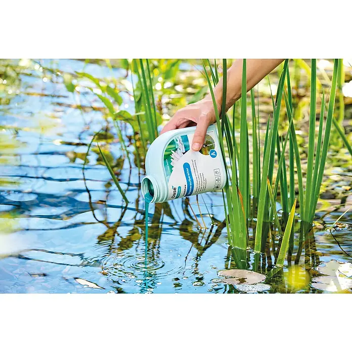 Oase AquaActiv Wasseraufbereiter AquaActiv - 500 ml - Jemand gießt Oase AquaActiv Wasseraufbereiter in einen Teich, um das Wasser sauber zu halten und das Wachstum von Algen zu verhindern.