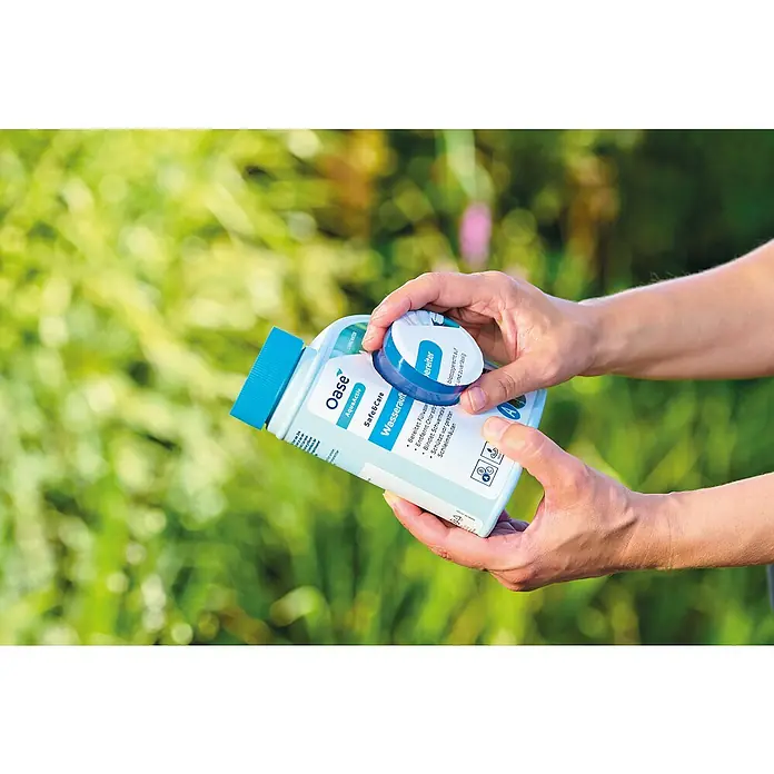 Oase AquaActiv Wasseraufbereiter AquaActiv - 500 ml - Oase AquaActiv Safe&Care Wasseraufbereiter wird von einer Person gehalten. Es verspricht eine sichere und gepflegte Wasseraufbereitung.