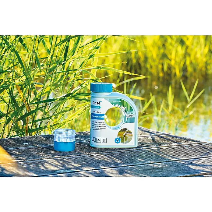 Oase AquaActiv Wasseraufbereiter AquaActiv - 500 ml - Produktaufnahme einer Flasche Oase AquaActiv Safe&Care Wasseraufbereiter neben einem Messbecher auf einem Holzsteg.