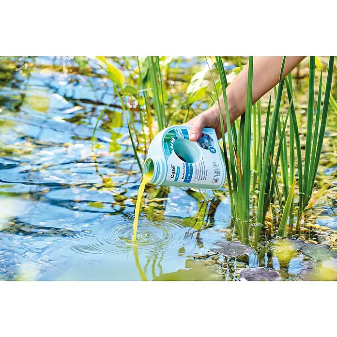 Oase AquaActiv Filterstarter - 500 ml - Eine Person gießt Oase BioKick Fresh Filterstarter in einen Teich, um das Teichwasser zu reinigen und das biologische Gleichgewicht zu fördern.