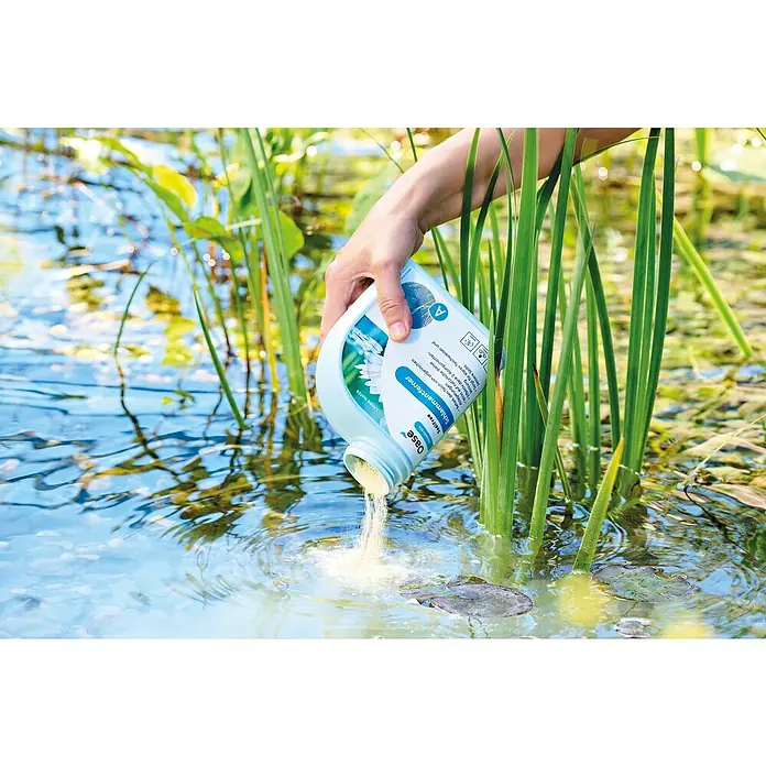 Oase AquaActiv Teichschlammentferner Sedifree - 500 ml - Eine Person gießt Oase Schlammentferner in einen Teich, um die Wasserqualität zu verbessern und Schlammablagerungen zu reduzieren.