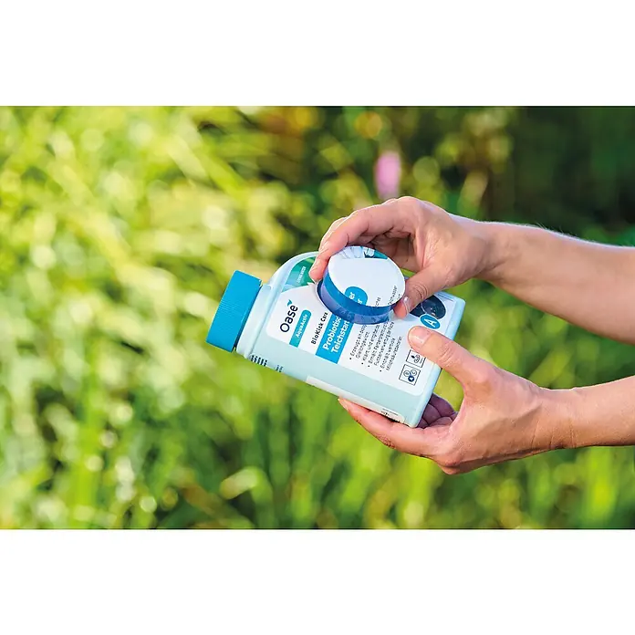 Oase AquaActiv Teichpflegemittel Probiotischer Teichstarter - 500 ml - Oase BioKick Care Probiotic Teichstart zur Förderung des biologischen Gleichgewichts im Teich, präsentiert von Händen.
