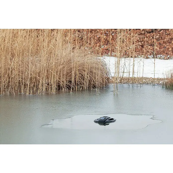 Oase Eisfreihalter IceFree 4 Seasons - Geeignet für: Gartenteiche - Das Bild zeigt einen schwarzen Teichreiniger auf einem zugefrorenen Teich, umgeben von trockenem Schilf und Schnee.