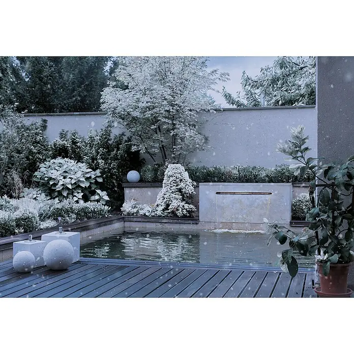 Oase LED-Beleuchtung Illumination 90 - Passend für: Oase Waterfall 90 - Winterliche Gartenszene mit einem Teich, umgeben von schneebedeckten Pflanzen und Dekorationen, die eine ruhige Atmosphäre schaffen.