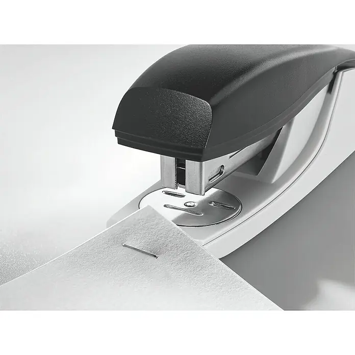 Leitz Heftgerät New NeXXt - L x B x H: 121 x 35 x 51 mm - Nahaufnahme eines weißen Tackergeräts mit schwarzem Oberteil, das ein Blatt Papier mit einer Klammer befestigt.
