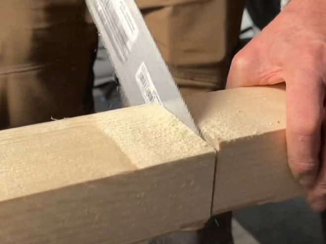 Mit einer Japansäge wird ein Rahmenholz zugeschnitten