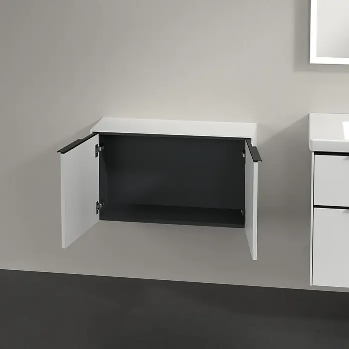 Villeroy & Boch Subway 3.0 Seitenschrank - B x T x H: 72,8 x 25,6 x 42,3 cm, Pure White, DIN Anschlag: Links/Rechts, Farbe Griff: Volcano Black - Weißer Waschbeckenunterschrank mit offenem Fach, montiert an einer grauen Wand.