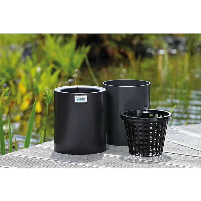 Oase Skimmer AquaSkim Gravity - Fördermenge pro Std.: 8.000 l - 20.000 l - Das Bild zeigt ein Oase-Produktset für Teichpflanzen, bestehend aus Pflanzgefäßen und einem Pflanzkorb, auf einer Holzterrasse vor einem Teich.