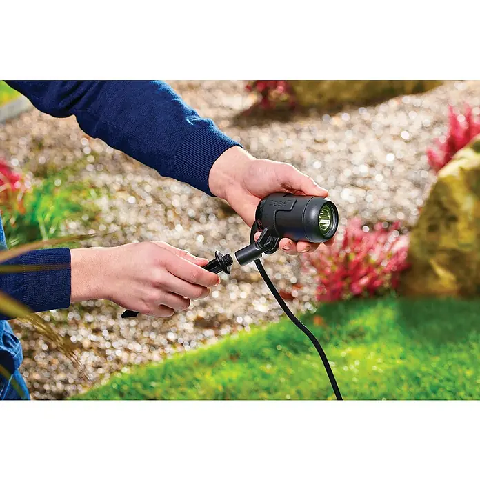 Oase LED-Spotstrahler LunAqua Connect S Set 3​ - Anzahl LED: 3 Stk., Warmweiß - Nahaufnahme einer Person, die eine Oase-Gartenleuchte mit Erdspieß für die Gartenbeleuchtung montiert.